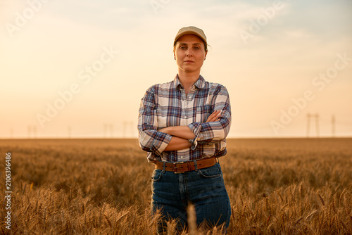 Female farmer standing confident in golden wheat field