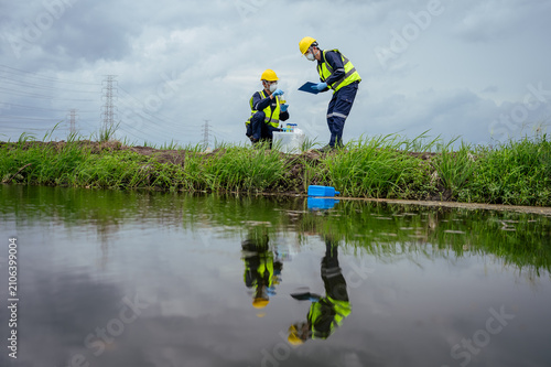 Environmental engineers conducting a water pollution inspection near power lines, reflecting on the water surface. Emphasizing ESG goals, corporate compliance, and ecological impact assessment.