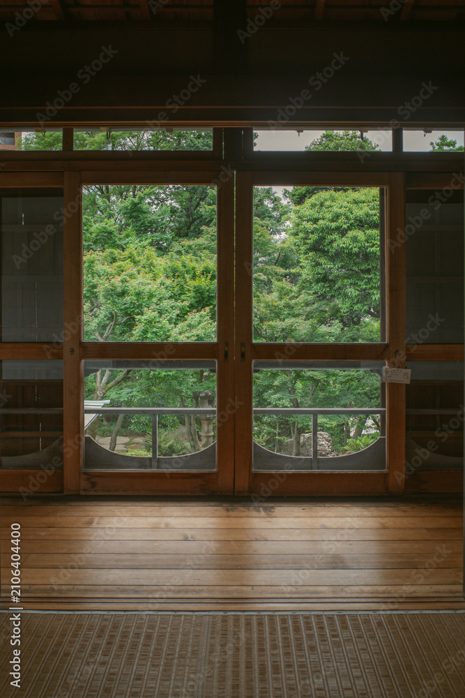 Fototapeta premium Traditional Japanese interior framing a lush green garden through wooden sliding screens and windows