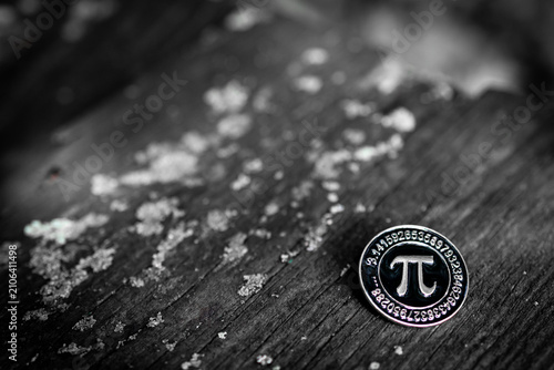 Фотография Minimal monochrome study of the pi sign on a coin placed on distressed wood capt