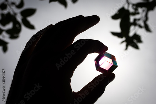 Obraz na plátně Compact glass cube shows shifting hues when held to the sun conveying STEM curio
