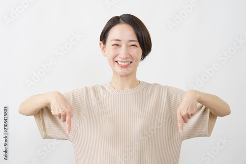 両手で下を指し示す女性　ミドルエイジ　白背景