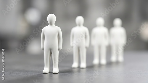 A line of white abstract human figurines standing on a grey surface, representing leadership, individuality, and teamwork in a business concept