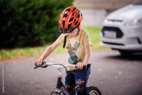 Canvas Print Little kid riding bicycle in suburban neighborhood wearing protective headgear d