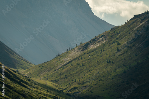фотографія Breathtaking view of the Italian Alps near Livigno, where sunlight highlights green mountain slopes beneath towering peaks