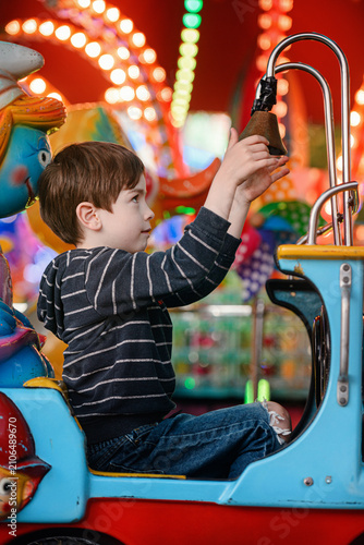 Low angle pensive boy in high red car ride framed by helicopter at dusk