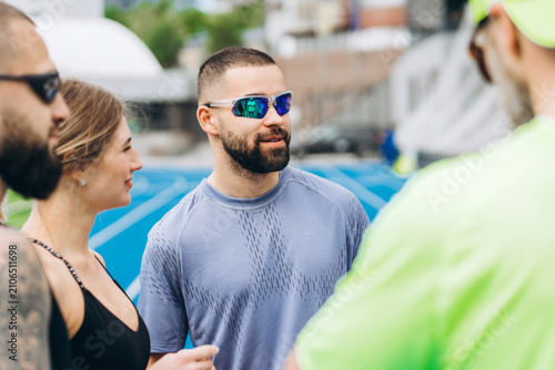 Photos Male runner talking with teammates before outdoor workout