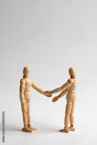 two wooden figures shaking hands