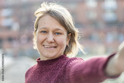 фотографія Smiling mid-adult woman taking a selfie outdoors on a sunny day
