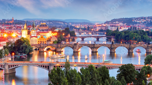 Foto Twilight cityscape featuring multiple bridges over a river in Prague skyline, with historic buildings and street lights