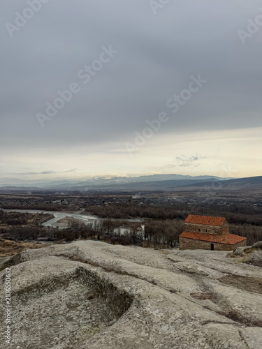 Ancient stone building on rocky hilltop overlooking river valley and mountains.