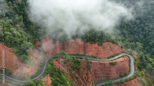 Bild auf Leinwand Aerial View of Winding Mountain Road Through Red Cliffs and Tropical Rainforest
