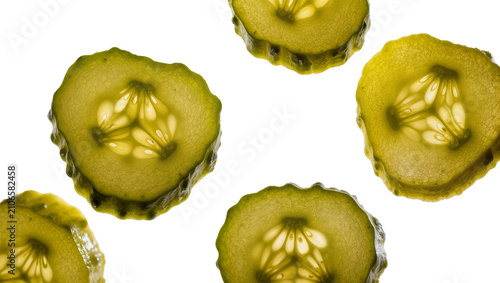 Isolated multiple thin backlit pickle slices showing translucent texture and seeds.