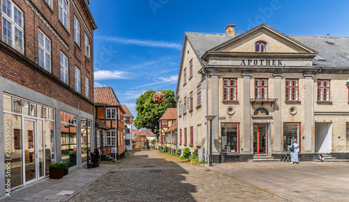 Charming European cobblestone street in historic town. Quaint Scandinavian village scene with colorful old buildings and clear blue sky. Faaborg, Denmrk