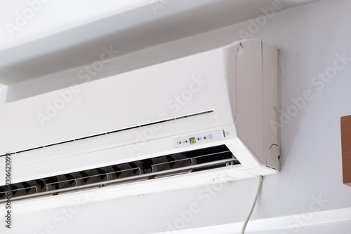 Close up of a wall mounted split air conditioner displaying temperature settings on control panel in modern room.