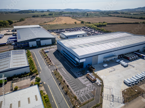 Aerial View of Modern Industrial Warehouse Complex in Green Countryside at Sunset – Commercial Buildings in Rural Setting