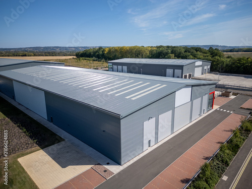 Aerial View of Modern Industrial Warehouse Complex in Green Countryside at Sunset – Commercial Buildings in Rural Setting