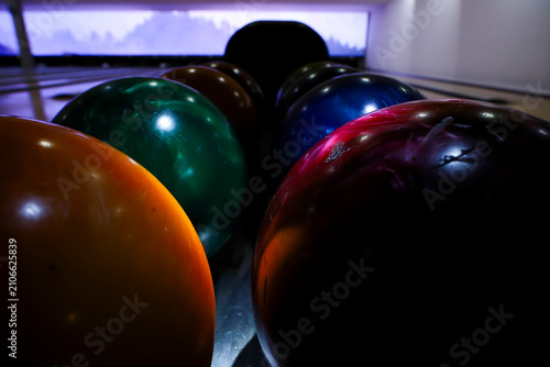 Aesthetic close up of colorful bowling balls at indoor bowling alley. Reflections, colorful spotlight highlighting equipment