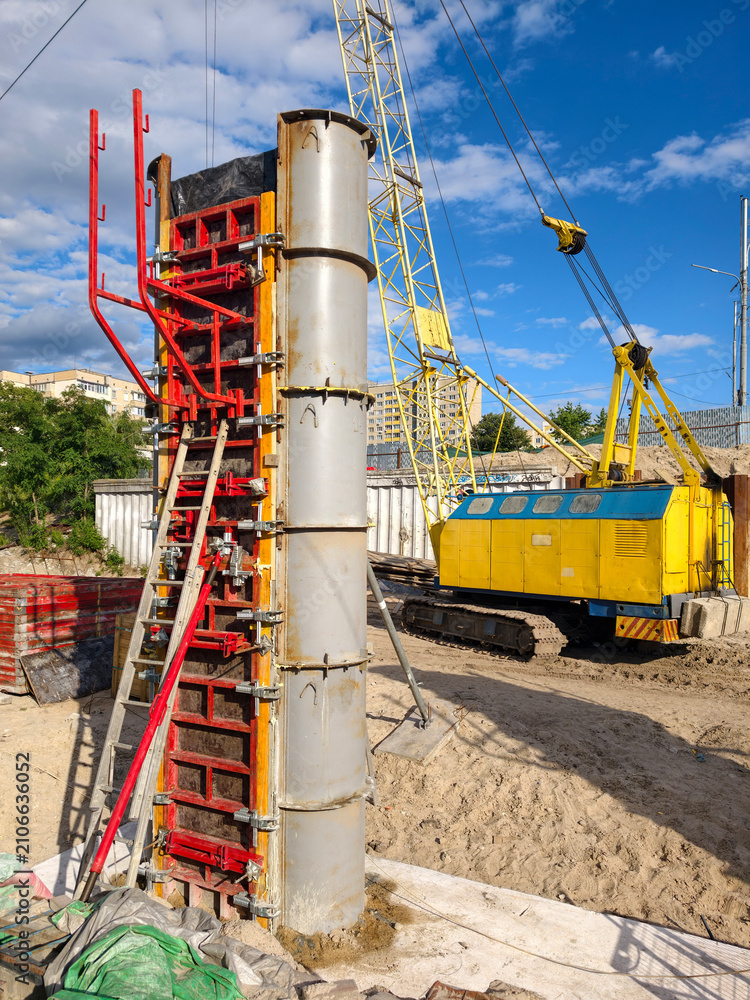 Fototapeta premium Construction site, yellow crawler crane and reinforced concrete bridge pier concreting using modular formwork demonstrating structural mechanics and controlled load distribution in civil engineering