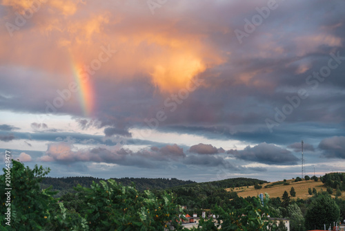 Rainbow on a stormy sky, with wind turbines and a GSM mast in the background, Kamienna Góra, Poland.