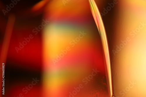 Luminous rainbow spectrum refracted through soap film boundary. Light splits into a soft spectrum of warm amber, magenta, and green across a thin fluid membrane.