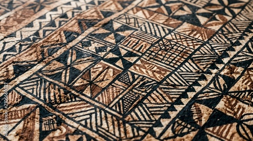 Traditional pacific island tapa cloth features intricate geometric patterns with earthy brown and black ink textures captured in soft focus