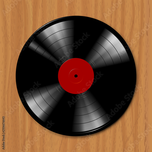 Vintage vinyl record spins on wooden surface. Red center contrasts with black grooved disc. Warm wood grain adds rustic charm. Perfect for retro music or vintage design themes