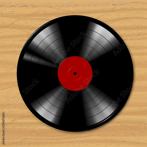 Black vinyl record spins on wooden surface. Red center contrasts with dark grooves. Smooth motion suggests music or nostalgia. Ideal for music, retro, or vintage themes. Natural wood grain adds warm
