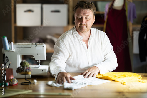 Canvastavla Middle-aged male dressmaker reviewing finished child dress