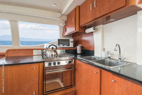 Cuadro en lienzo Clean and modern galley kitchen of a charter private sailing catamaran with wood