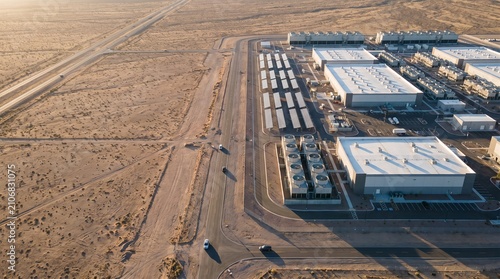 Aerial view of a massive data center facility and cooling towers located in a desert landscape with copy space