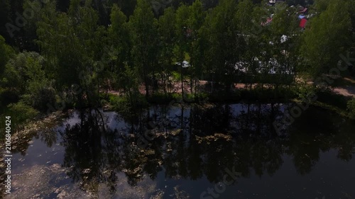 A flight over a lake with a right turn along the reed-covered shore on a sunny summer day. Lake Berezovoe, Novosibirsk, Russia.