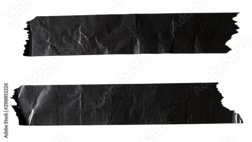 Isolated black masking tape pieces with ragged edges and wrinkled, textured surface.