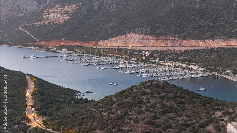 Fototapeta premium Aerial View of Kas Marina at Dusk: Yachts, Breakwater, and Coastal Lights in Turkey.