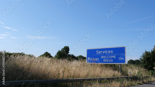 Motorway road sign, UK highway sign, British services direction sign, M6 motorway route with blue sky and dry grass on roadside