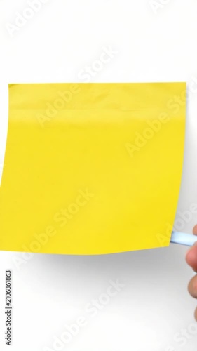 Single yellow post-it note standing upright against a grey surface.