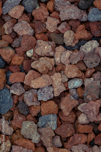 Obraz na plátně Top-down view of textured volcanic lava rocks in deep terracotta, crimson, and charcoal grey tones