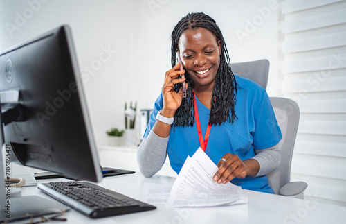 Foto Female nurse communicating on phone while working in office