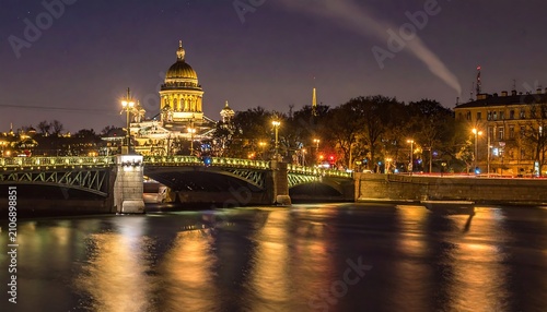 A nighttime cityscape with a large domed building and bridge over a river