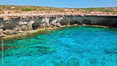 Drone view of Cape Cavo Greco coastline in Cyprus. Clear turquoise sea, curved rocky bay and pale limestone shore create a peaceful summer seascape.