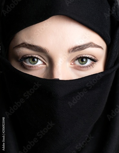 Woman's striking green eyes framed by dark fabric