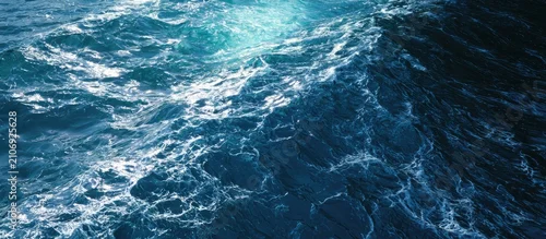 Obraz  z motywem Raging blue ocean waves churn with white foam under bright light