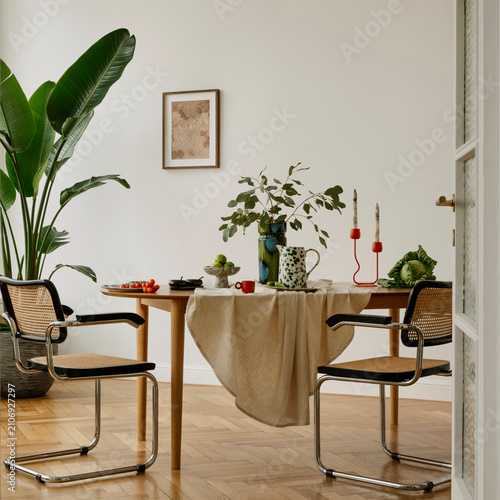 Dining table with lush greenery, playful red candleholders, and a mix of textures. A cozy and creative interior blending plants, textiles, and colorful ceramics.