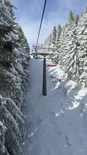 Snow-covered ski slope in the mountains above Andalo ski resort in the Italian Eastern Alps, view from the chairlift.
