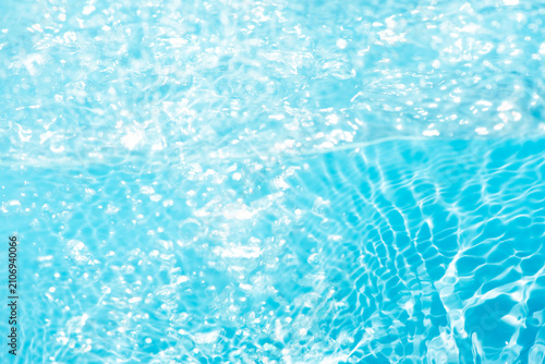 Blue water with ripples on the surface. Defocus blurred transparent blue colored clear calm water surface texture with splashes and bubbles. Water waves with shining pattern texture background.