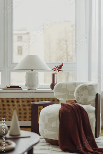 Cozy Living Room Corner with Modern Armchair, Table Lamp, and Window View in a Bright Apartment Interior