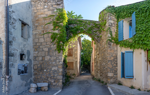 Puimoisson, France - 07 05 2026: Panoramic view of typical Riez Portal, street, houses and medieval ramparts of the hilltop village under a blue sunny sky