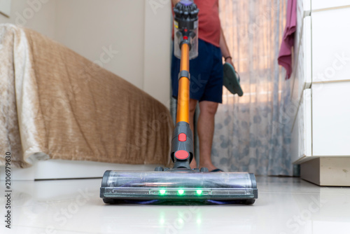 Foto Person using a modern cordless vacuum cleaner with led lights, cleaning the smoo