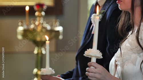 Couple holding lit candles during solemn church wedding ceremony