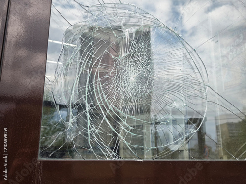 Broken glass in a window showing signs of damage in a city area on a cloudy day